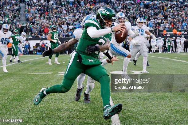 Zach Wilson of the New York Jets runs with the ball as DeShon Elliott of the Detroit Lions defends during the second half at MetLife Stadium on...
