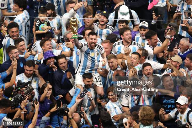 Lionel Messi of Argentina celebrates with the FIFA World Cup Qatar 2022 Winner's Trophy on the shoulders of former teammate Sergio Aguero after the...