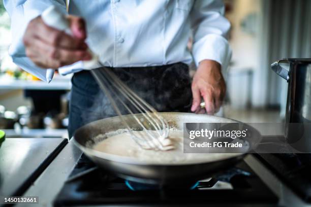 chefkoch bei der zubereitung von soße in einer großküche - sahnesoße stock-fotos und bilder