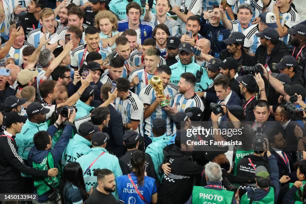 Former Argentina forward Sergio Aguero admires the trophy with Lionel Messi of Argentina following the FIFA World Cup Qatar 2022 Final match between...