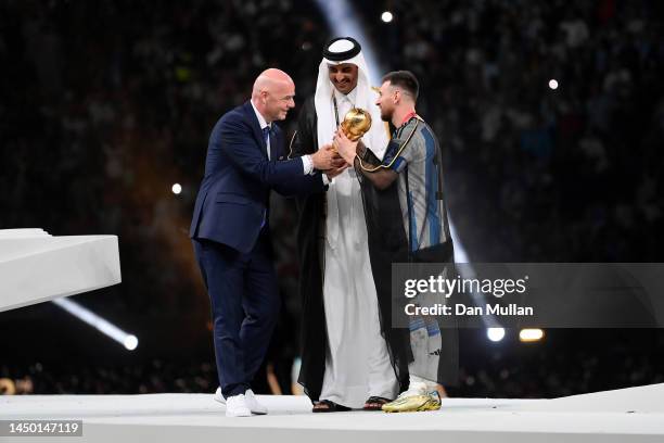 Lionel Messi of Argentina carries the FIFA World Cup Qatar 2022 Winner's Trophy as Gianni Infantino, President of FIFA, and Sheikh Tamim bin Hamad Al...