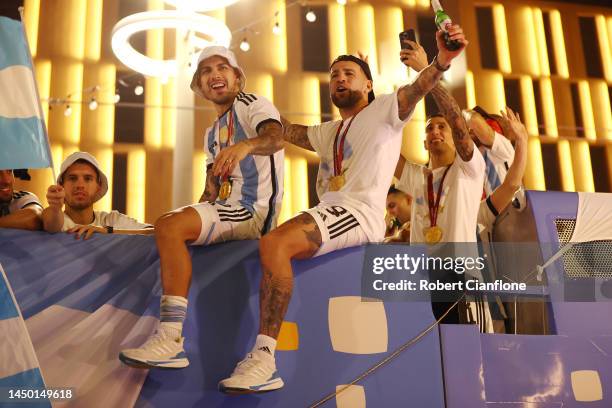 Leandro Paredes and Nicolas Otamendi of Argentina celebrate after winning the FIFA World Cup on an open top bus outside the stadium after the FIFA...