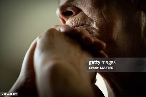 senior woman sitting alone in silence - hand on head stockfoto's en -beelden