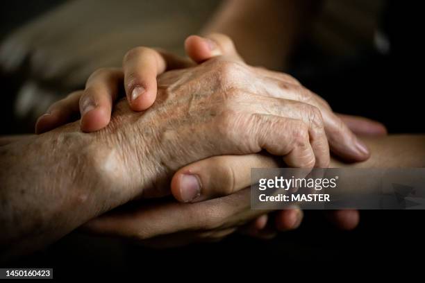 young holding elderly hands for care and love - general hospital stock pictures, royalty-free photos & images