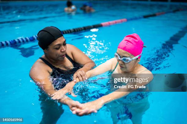 senior woman learning to swim in the swimming pool - swimming lessons stock pictures, royalty-free photos & images