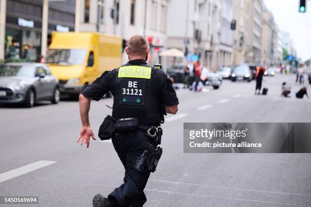 Policeman runs on Friedrichstraße to avoid sticking activists of the climate protection group Letzte Generation. Last Generation protests against the...