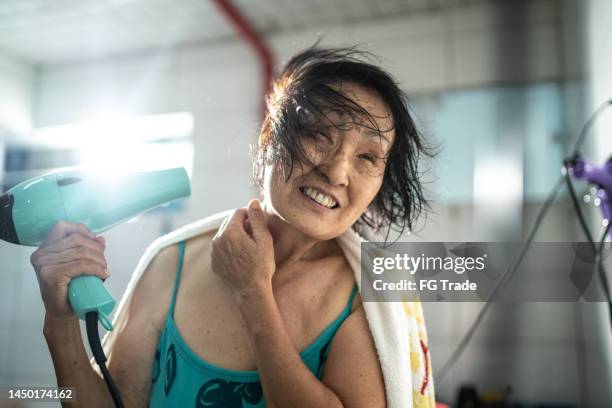 seniorin föhnt haare nach dem schwimmkurs - haare föhnen stock-fotos und bilder