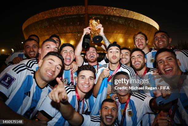 Alexis Mac Allister of Argentina celebrates with teammates and The FIFA World Cup Qatar 2022 Winner's Trophy after winning the FIFA World Cup on an...