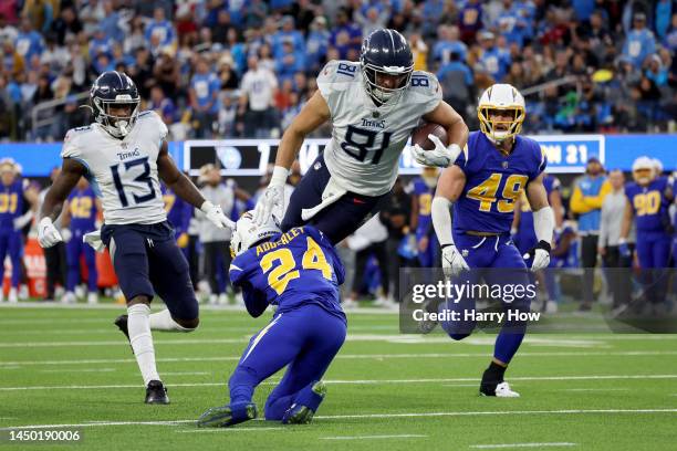 Austin Hooper of the Tennessee Titans catches the ball while being tackled by Nasir Adderley of the Los Angeles Chargers during the fourth quarter of...