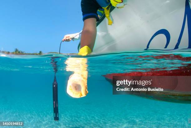 marine biologist taking samples of water from a boat for water quality test - marine biologist stock pictures, royalty-free photos & images
