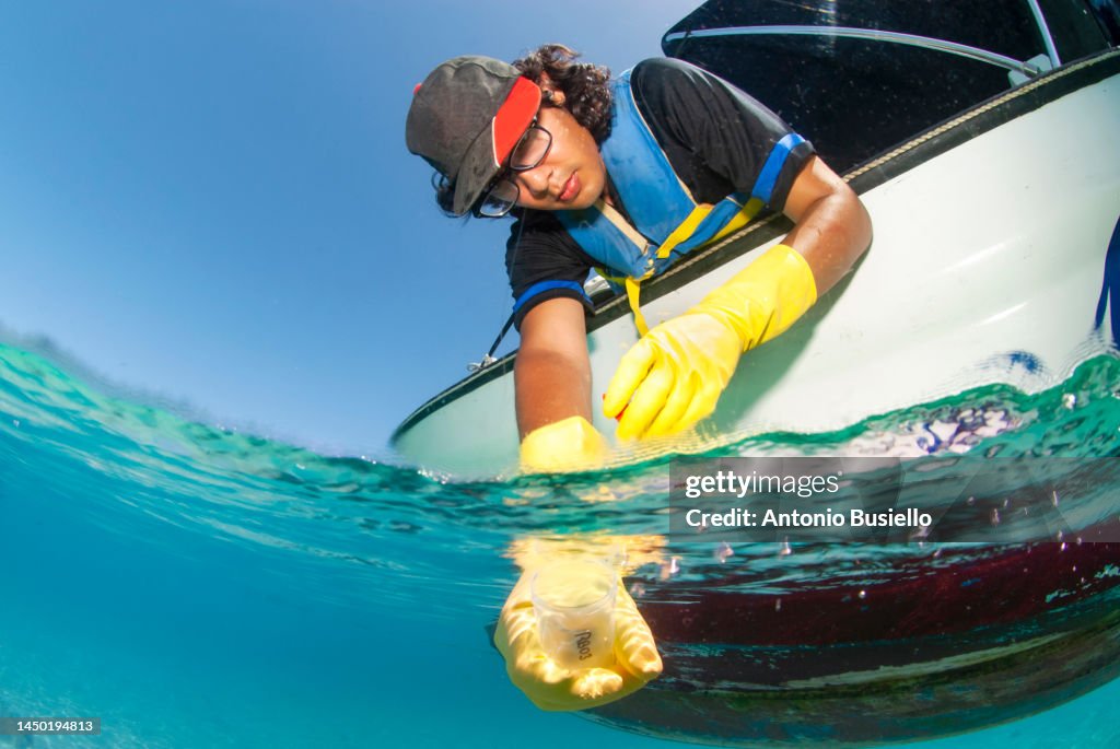 Marine Biologist taking samples of water from a boat for water quality test