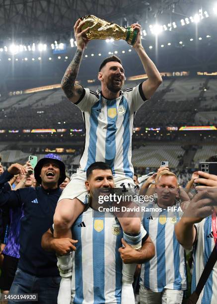 Lionel Messi of Argentina celebrates with the FIFA World Cup Qatar 2022 Winner's Trophy on Sergio 'Kun' Aguero's shoulders after the team's victory...