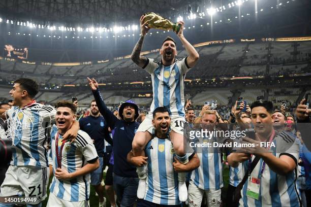 Lionel Messi of Argentina celebrates with the FIFA World Cup Qatar 2022 Winner's Trophy on Sergio 'Kun' Aguero's shoulders after the team's victory...
