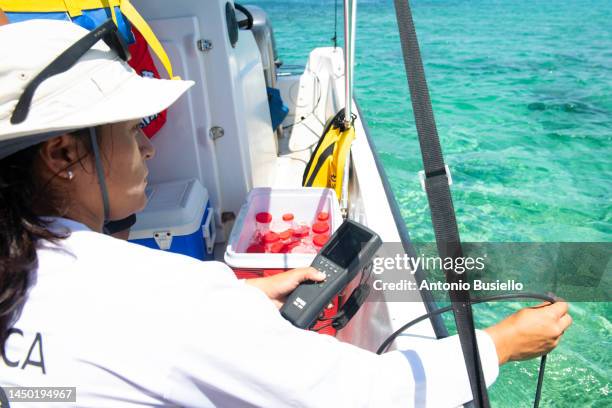 female marine biologist taking samples of water from a boat for water quality test - marine biologist stock pictures, royalty-free photos & images