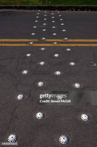 rows of small speed bumps on a bitumen road with yellow double line marking - bumpy road stock pictures, royalty-free photos & images