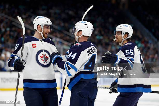 Pierre-Luc Dubois, Josh Morrissey and Mark Scheifele of the Winnipeg Jets celebrate a goal during the first period against the Seattle Krakenat...