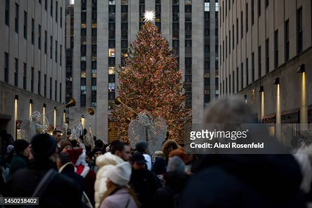 People walk past the Rockefeller Christmas Tree on Fifth Avenue during the Open Streets program during its last day on December 18, 2022 in New York...