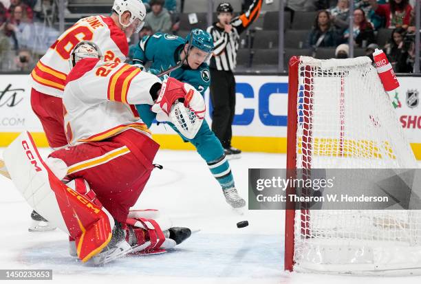 Nico Sturm of the San Jose Sharks shoots on goal and misses the shot going past the goal behind goal keeper Jacob Markstrom of the Calgary Flames...