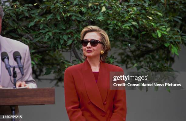 American First Lady of the United States Hillary Clinton, wearing a red suit and sunglasses, attends a meeting with the League of Women Voters, held...