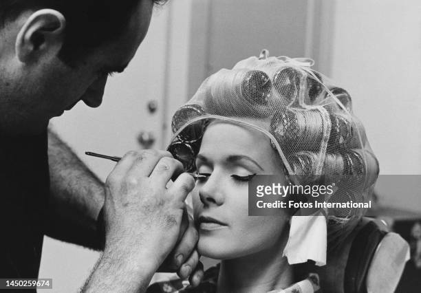 American actress and singer Connie Stevens her eyes closed as an make-up artist applies mascara to Stevens' eyelashes on the set of an film, United...