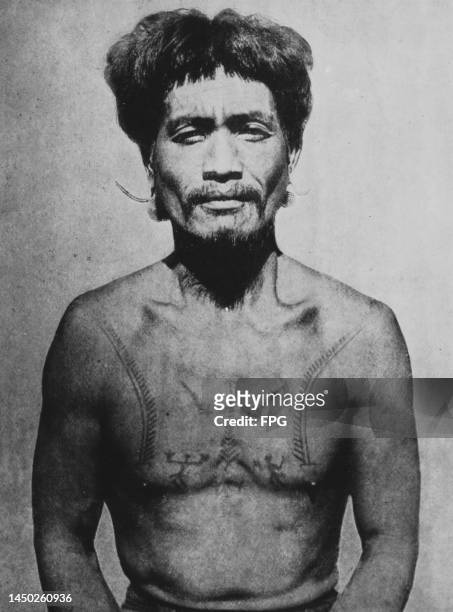 An Igorot man, with a tattooed torso, Philippines, circa 1915. The Igorot people are the indigenous peoples of the Cordillera Mountain Range of...