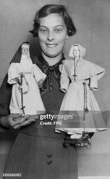 British actress Celia Johnson holding two eighteenth-century dolls, each dressed as a nun, at Hamleys toy shop on Regent Street in the West End of...