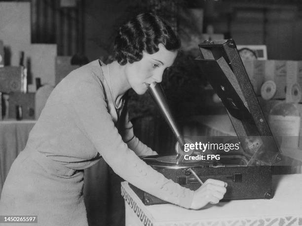 Woman speaks into the 'speaking trumpet' of a home recorder for making records without the aid of electricity, during preparations ahead of the...