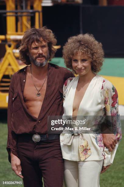 American singer, songwriter and actor Kristoffer Kristofferson, wearing an open brown shirt, with his arm around American singer and actress Barbra...