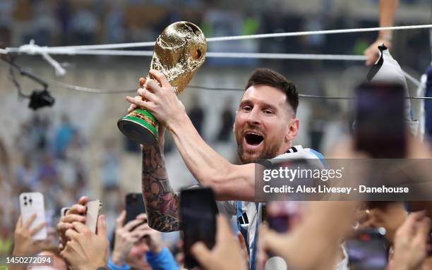 Lionel Messi of Argentina celebrates with the World Cup trophy with supporters while on the shoulders of Sergio 'Kun' Aguero after the FIFA World Cup...