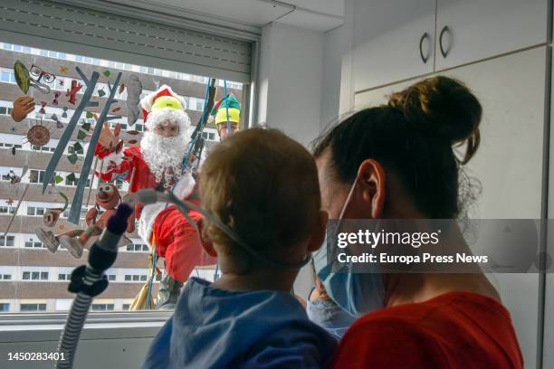 Santa Claus greets a child in hospital to give him a present as he hangs on the façade of the Germans Trias i Pujol University Hospital , on 19...