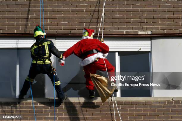 Fireman and Santa Claus hang from the facade of the Germans Trias i Pujol University Hospital to give presents to the children in the hospital, on 19...