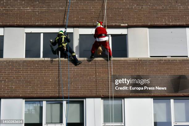 Fireman and Santa Claus hang from the facade of the Germans Trias i Pujol University Hospital to give presents to the children in the hospital, on 19...