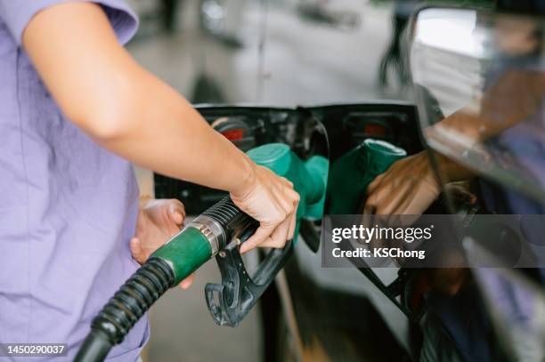 woman refueling the car at the gas station - refuelling stock pictures, royalty-free photos & images