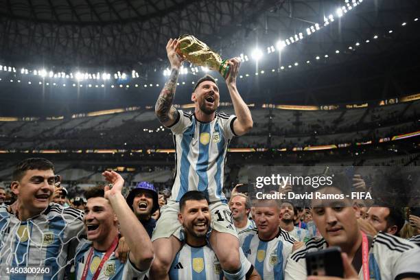 Lionel Messi of Argentina celebrates with the FIFA World Cup Qatar 2022 Winner's Trophy on Sergio 'Kun' Aguero's shoulders after the team's victory...
