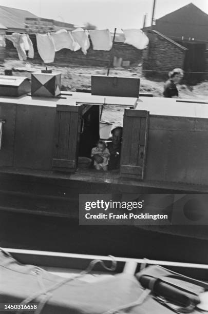 Residents at the shuttered window of their narrow boat on the Grand Union Canal, England. Picture Post - 7798 - The Scandal of our Waterways - Volume...