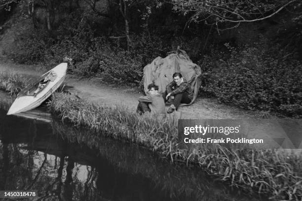 Two young men sitting with their boat on the towpath of the Grand Union Canal, England. Original Publication: Picture Post - 7798 - The Scandal of...