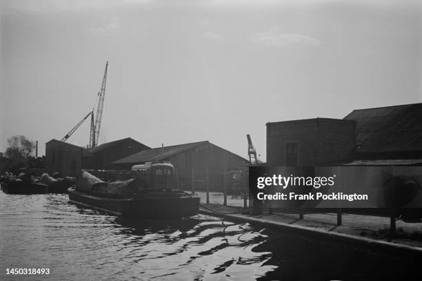 Cargo barge is moored next to industrial buildings on the Grand Union Canal, England. Original Publication: Picture Post - 7798 - The Scandal of our...