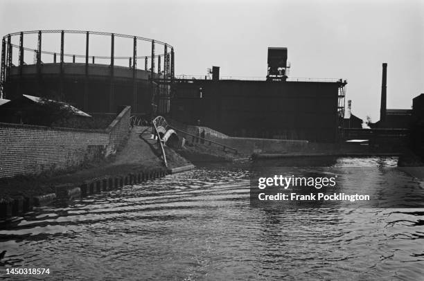 Bridge and towpath on the Grand Union Canal with industrial buildings and a gasometer visible in the background, England. Original Publication:...