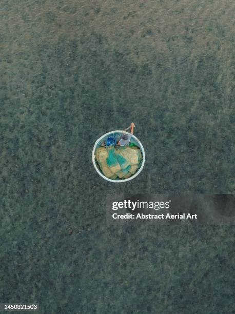 drone image looking down on a fisherman in a circular shaped rowing boat, vietnam - minimal effort stock pictures, royalty-free photos & images