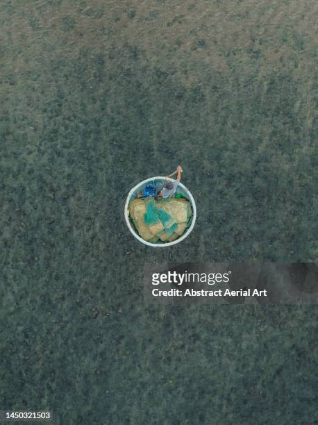 drone image looking down on a fisherman in a circular shaped rowing boat, vietnam - heritage round one imagens e fotografias de stock