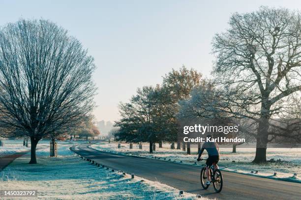 an unrecognisable cyclist in a frosty london park - winter cycling stock pictures, royalty-free photos & images