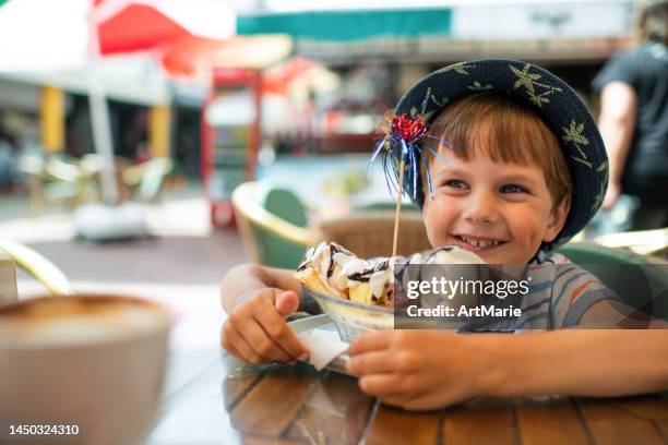 cute little boy eats ice-cream in a cafe - banana split stock pictures, royalty-free photos & images