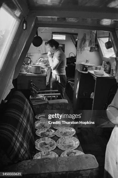 Woman cooking food in the kitchenette of a narrow boat on the Grand Union Canal, England. Original Publication: Picture Post - 7798 - The Scandal of...