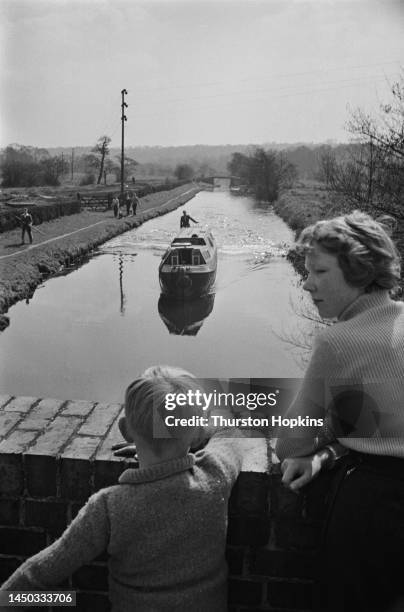 Children standing on a bridge watch an approaching narrow boat on the Grand Union Canal , England. Original Publication: Picture Post - 7798 - The...