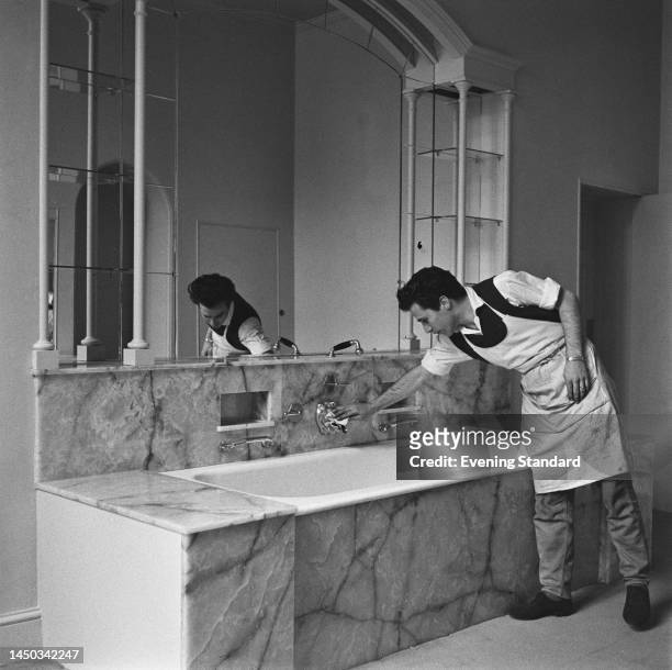 Workman cleaning taps in one of the bathrooms at J Paul Getty's Sutton Place mansion in Surrey, in preparation for a party on July 2nd, 1960.