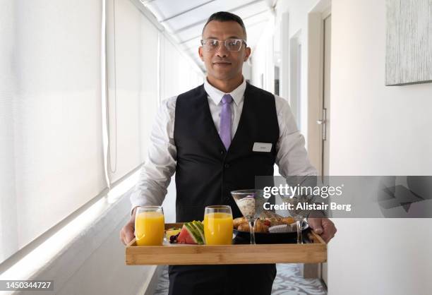 waiter delivering breakfast to luxury hotel room - bellhop stock pictures, royalty-free photos & images