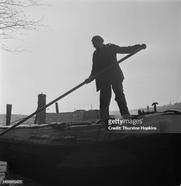 Man using a barge pole to push away from the towpath on the Grand Union Canal, England. Original Publication: Picture Post - 7798 - The Scandal of...
