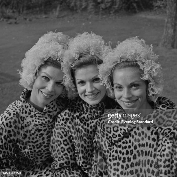 American singing trio the McGuire Sisters wearing matching hats and leopard print coats during a visit to London on October 16th, 1961. They are...