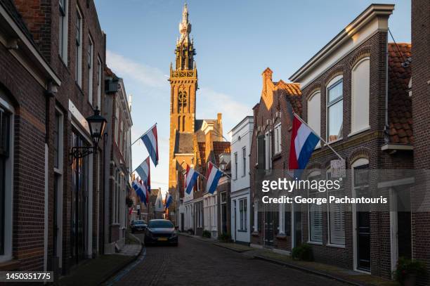 street with dutch flags and bell tower in edam - bell tower tower stock-fotos und bilder