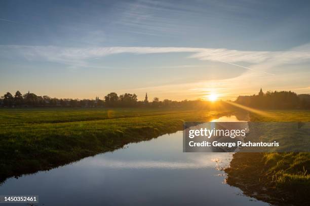 sunset over a calm canal and agricultural fields - netherlands sunset stock pictures, royalty-free photos & images